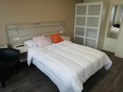 a bedroom with a large white bed with two pillows at Pensión La Intermodal in Santiago de Compostela