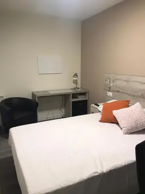 a bedroom with a white bed and a desk at Pensión La Intermodal in Santiago de Compostela