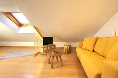 a living room with a yellow couch and a tv at VM Apartamentos Turísticos in Santiago de Compostela