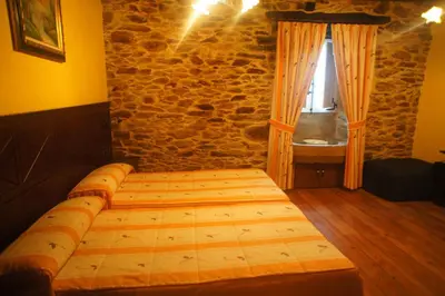 a bed in a room with a stone wall at Mirador Da Ribeira in Viana do Bolo
