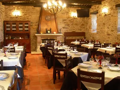 a restaurant with white tables and chairs and a fireplace at Mirador Da Ribeira in Viana do Bolo