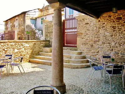 a group of chairs and tables in a patio with a pillar at Mirador Da Ribeira in Viana do Bolo