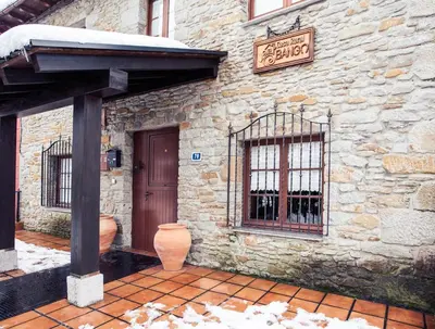 a stone building with a door and a sign on it at Casa Rural Bango in Caboalles de Abajo