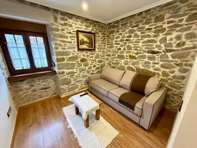 a living room with a couch and a stone wall at Casa Rural Bango in Caboalles de Abajo