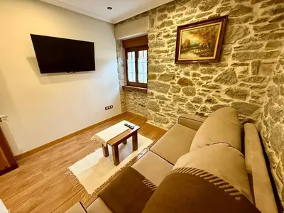 a living room with a couch and a stone wall at Casa Rural Bango in Caboalles de Abajo