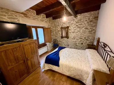 a bedroom with a bed and a flat screen tv at Casa Rural Bango in Caboalles de Abajo