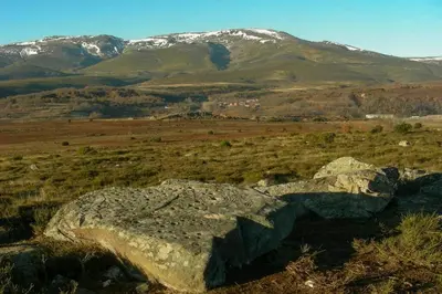 a large rock in a field with snow covered mountains at CASA CAMARGA in Santiago Millas