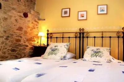 a bedroom with a bed with white sheets and pillows at CASA CAMARGA in Santiago Millas