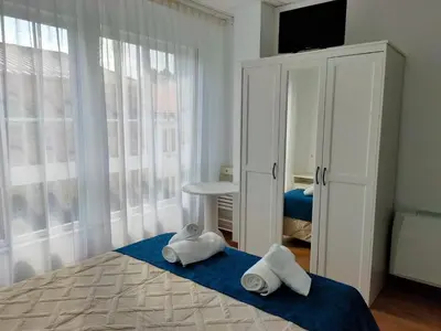a bedroom with two towels on a bed with a window at Lar do Peregrino in Palas de Rei