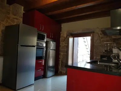 a kitchen with a white refrigerator and red cabinets at CAPELA DA GRANXA in Pontevedra