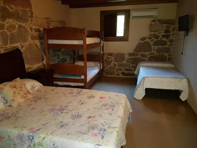 a bedroom with two beds and a stone wall at CAPELA DA GRANXA in Pontevedra