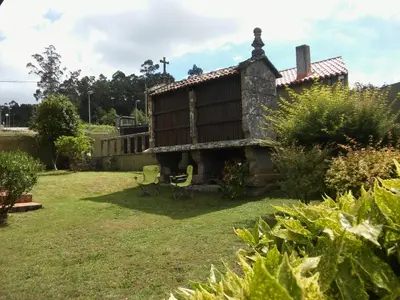 a house in a garden with two chairs at Casa Camino Santiago-Fisterra in Amés