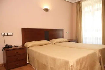 a bedroom with two twin beds and a window at Hotel Restaurante Casa Pipo in Tuña