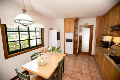 a kitchen with a table and a refrigerator and a table and chairs at Camiño da Vieira in Padrón