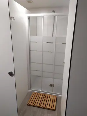 a walk in shower with a wooden mat in a bathroom at Camiño da Vieira in Padrón