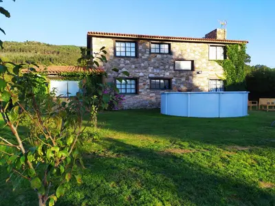 a stone house with a white fence in the yard at Camiño da Vieira in Padrón