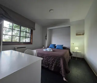 a bedroom with a bed with blue pillows and a window at Camiño da Vieira in Padrón