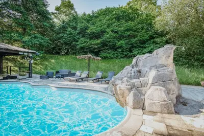 a swimming pool with chairs and an umbrella at Villa en Asturias con cine, Piscina, BBQ, Juegos, 14 Pax in Cobre