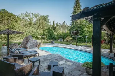 a swimming pool with chairs and an umbrella at Villa en Asturias con cine, Piscina, BBQ, Juegos, 14 Pax in Cobre