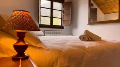 a bedroom with a bed with a lamp and a window at Apartamentos rurales La Pornacal I y La Pornacal II in Villar de Vildas