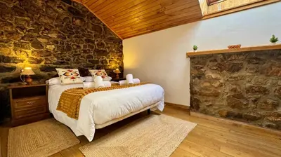 a bedroom with a bed and a stone wall at Apartamentos rurales La Pornacal I y La Pornacal II in Villar de Vildas