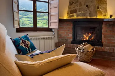 a living room with a fireplace and a couch at Apartamentos rurales La Pornacal I y La Pornacal II in Villar de Vildas