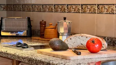 a kitchen counter with a cutting board with a tomato and avocado at Apartamentos rurales La Pornacal I y La Pornacal II in Villar de Vildas