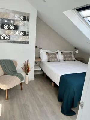 a bedroom with a large bed and a chair at CONCHEIROS 5 APARTAMENTOS TURISTICOS in Santiago de Compostela