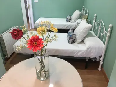 a vase with flowers on a table in a room with two beds at Hostal Restaurante Alarico in Allariz