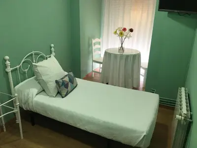 a bedroom with a bed and a table with a vase of flowers at Hostal Restaurante Alarico in Allariz