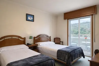 a hotel room with two beds and a window at Hotel San Rosendo in Ourense