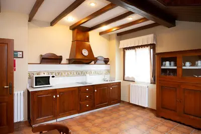 a kitchen with wooden cabinets and a microwave at As Tapias Apartamentos in Tapia de Casariego