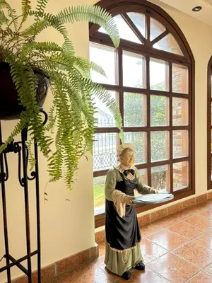 a statue of a woman sitting at a table near a window at As Tapias Apartamentos in Tapia de Casariego