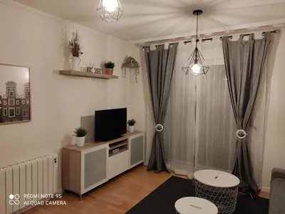 a living room with a tv on a stand with a curtain at AURINE in Foz