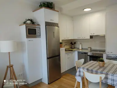 a kitchen with white cabinets and a table with chairs at AURINE in Foz