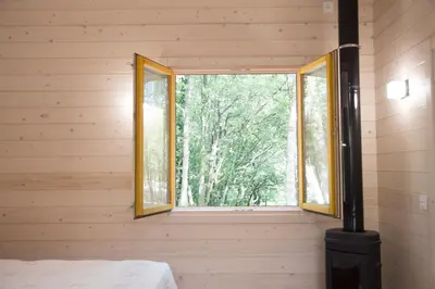 a bedroom with a window in a wooden wall at Cabanas da Ulla in Touro