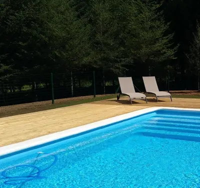 two white chairs sitting next to a swimming pool at Cabanas da Ulla in Touro