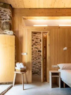 a bedroom with a bed and a stone wall at Abeiro da loba in Madelos