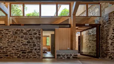 a large room with a stone wall and windows at Abeiro da loba in Madelos