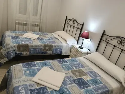 a bedroom with two beds and a lamp on a night stand at PISO BENITO in Ourense