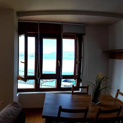 a dining room with a table and a large window at HOLIDAY HOMES Figueras AT in Castropol