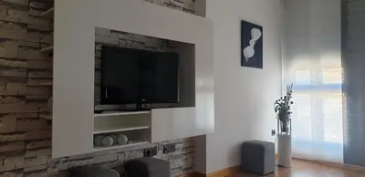 a living room with a tv on a brick wall at Apartamento tranquilo in Ponferrada