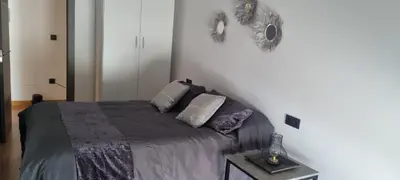 a bedroom with a bed with a gray blanket and pillows at Apartamento tranquilo in Ponferrada