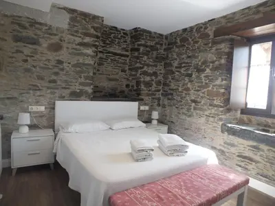 a bedroom with a bed and a brick wall at Apartamentos Puerta del Castro in Coaña