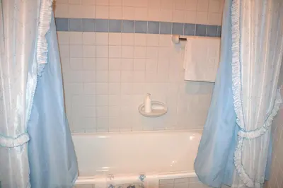 a bathroom with a tub with a blue shower curtain at Cabeza da Vila in San Martín de Oscos