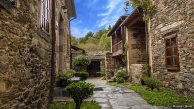 an alley in an old stone building with plants at Cabeza da Vila in San Martín de Oscos