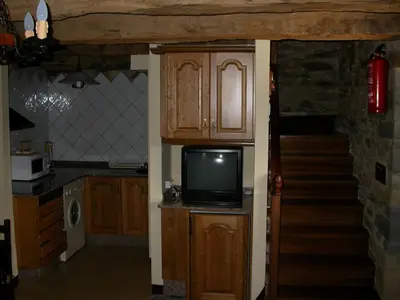 a kitchen with a tv on a counter and a staircase at Casa de Alba in San Martín de Oscos