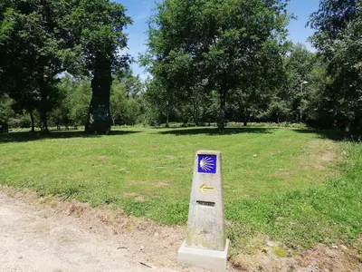 a sign in the middle of a field with trees at Alojamiento Camiño Real in Sigüeiro