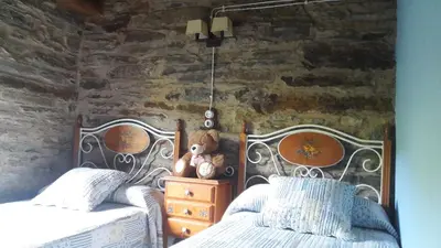 a bedroom with two beds and a stone wall at O Paxar in Samos