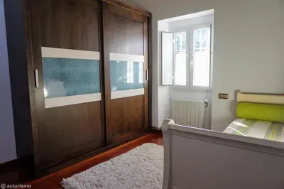 a bedroom with a wooden door and a bed and a window at O Rincón de Mercedes in Jove